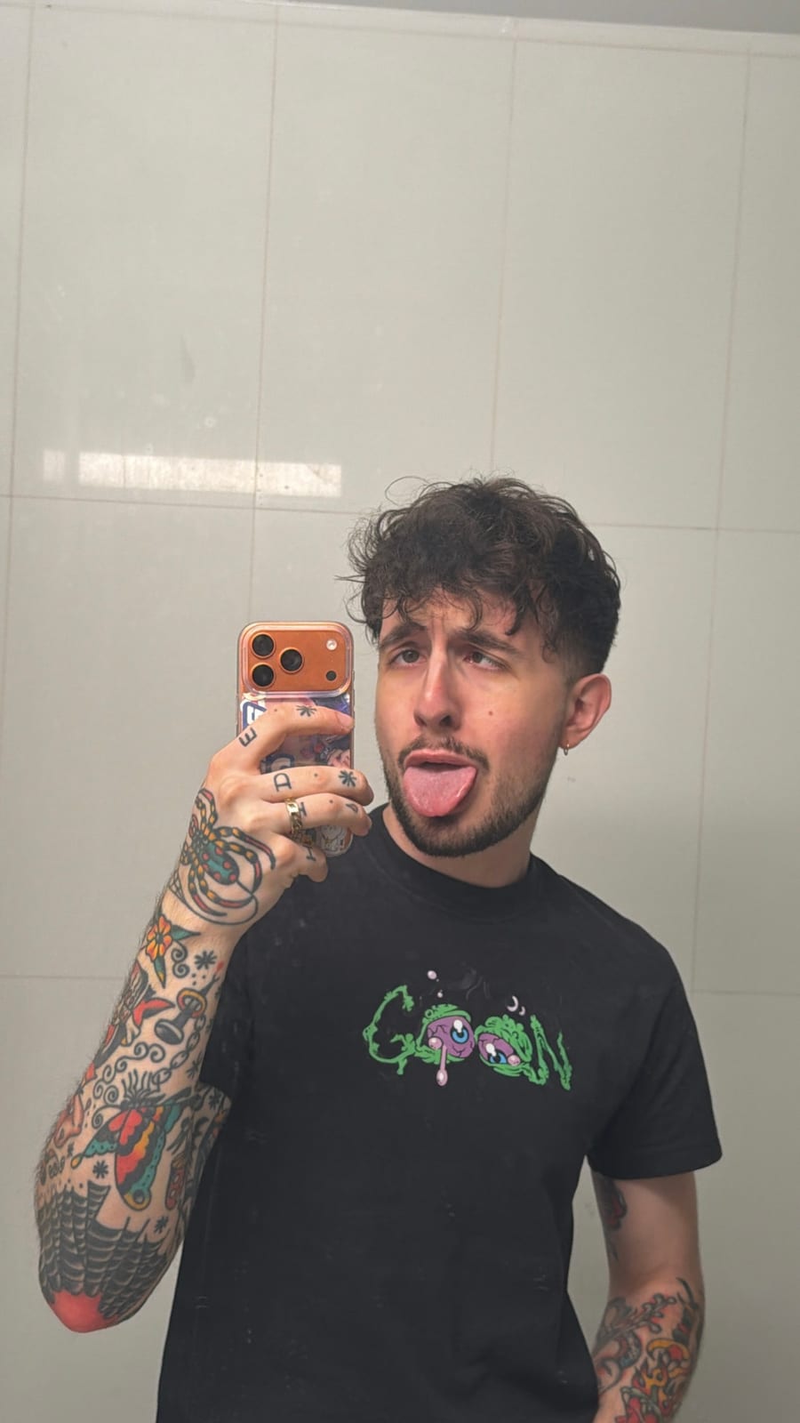 Andres taking a mirror selfie in a black graphic T-shirt