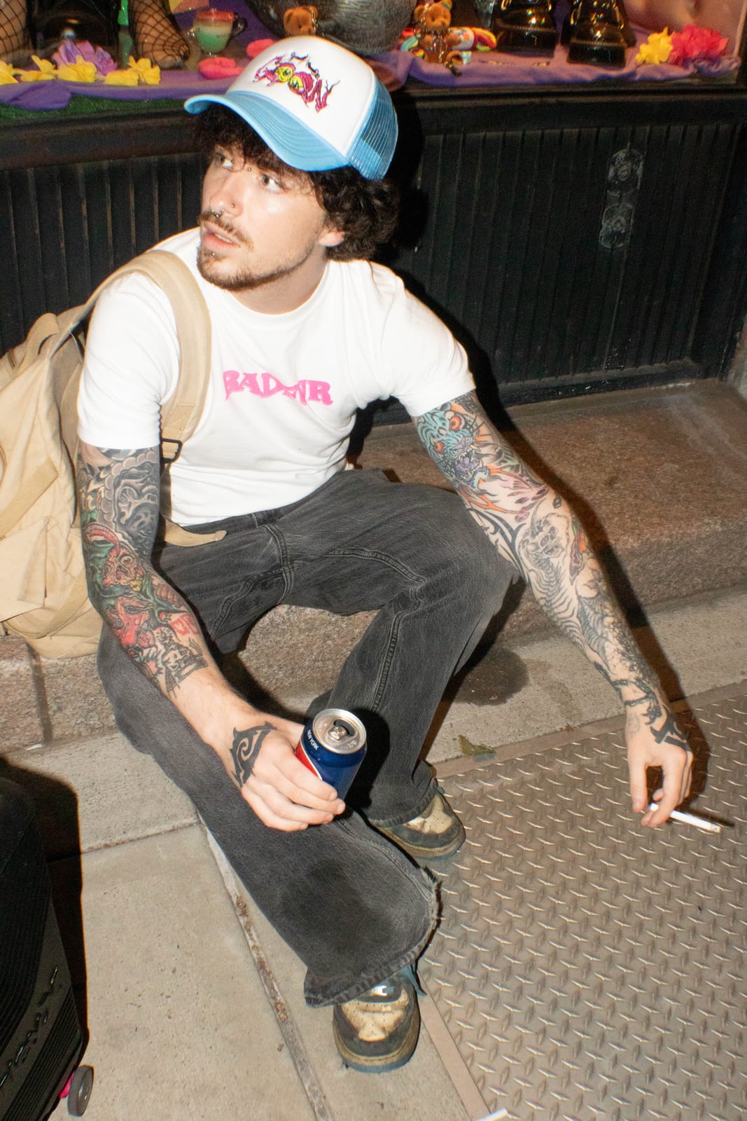 Clay sitting outside in a BadFur T-shirt and trucker hat
